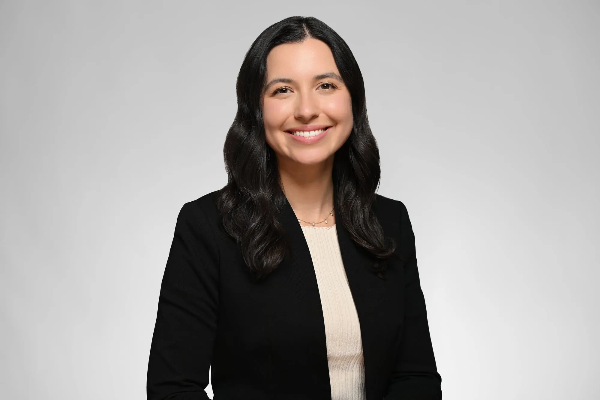 ERAS-ready medical residency headshot: black blazer over a cream top, grey background
