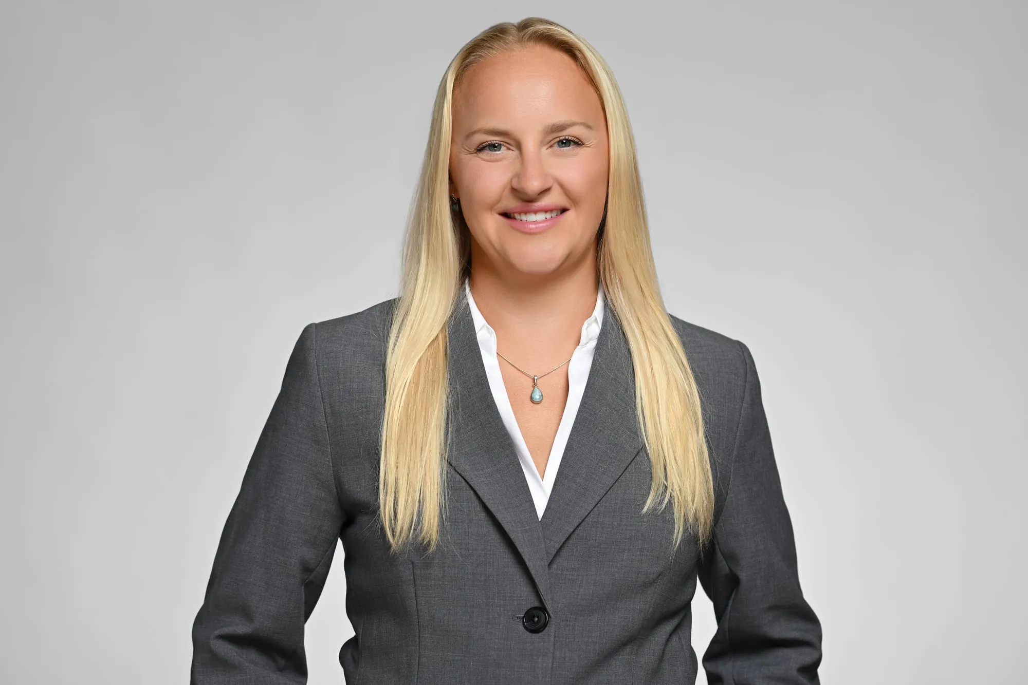 ERAS-ready medical residency headshot: grey suit and long blonde hair, grey background