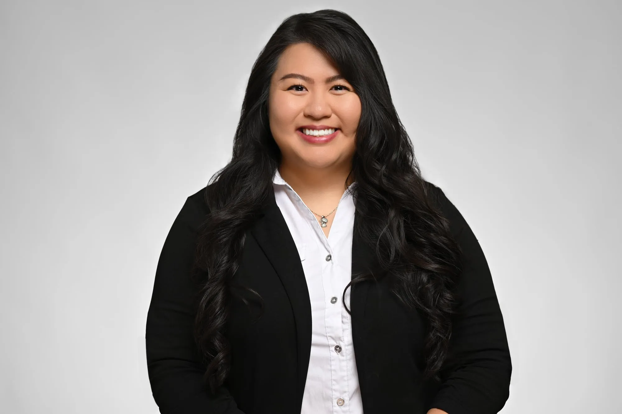 ERAS-ready medical residency headshot: black blazer and white shirt, grey background