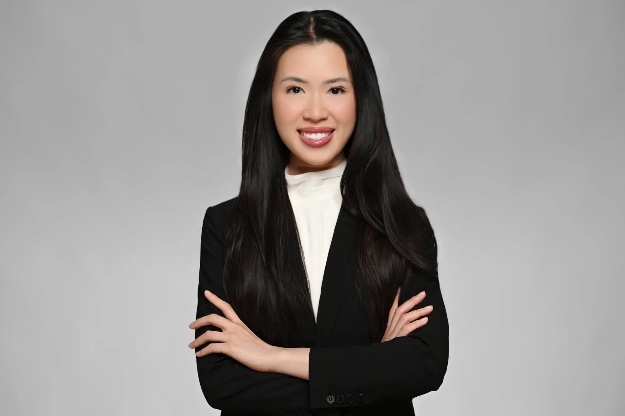 ERAS-ready medical residency headshot: black suit, arms crossed, grey background
