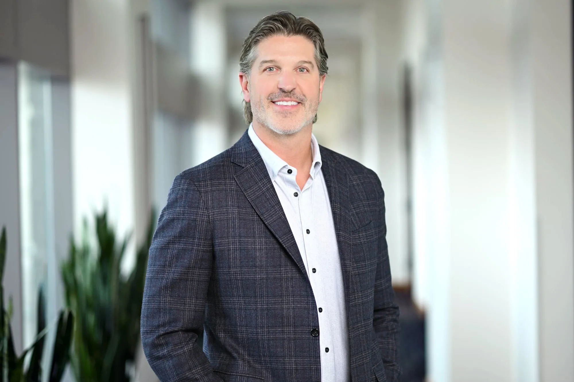 On-location headshot in Denver: check blazer in a bright modern office corridor