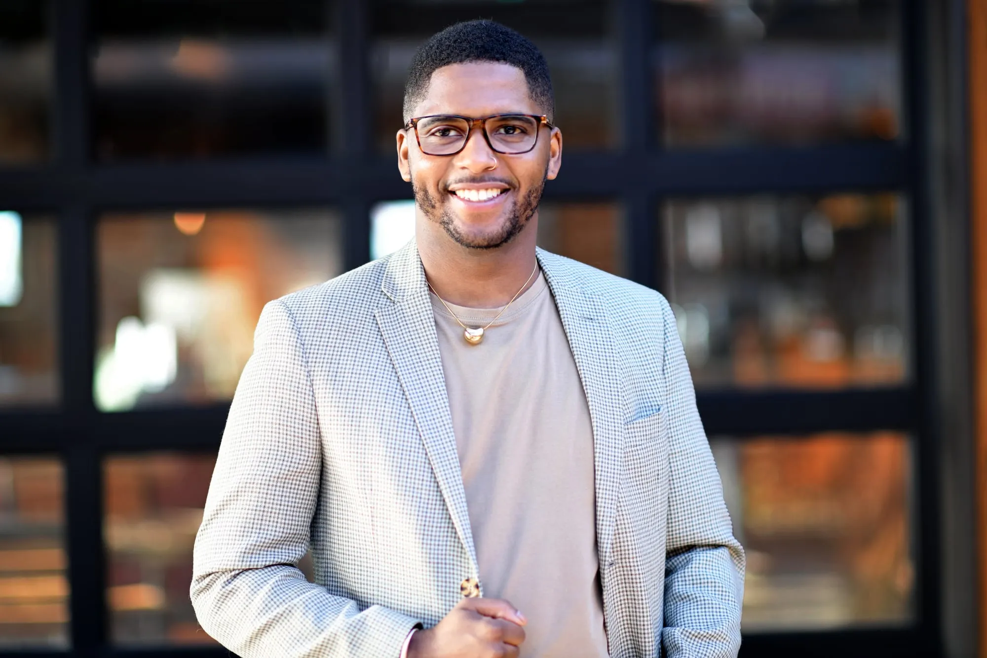 On-location headshot in Denver: light blazer and glasses in front of restaurant windows