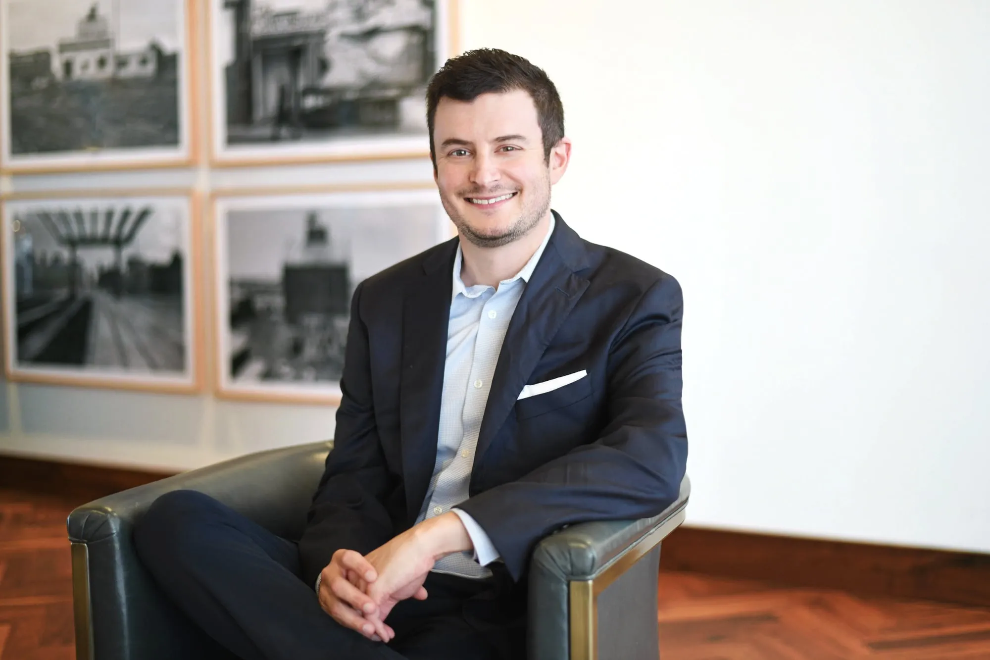 On-location headshot in Denver: seated in a leather chair in a lobby with framed photos behind