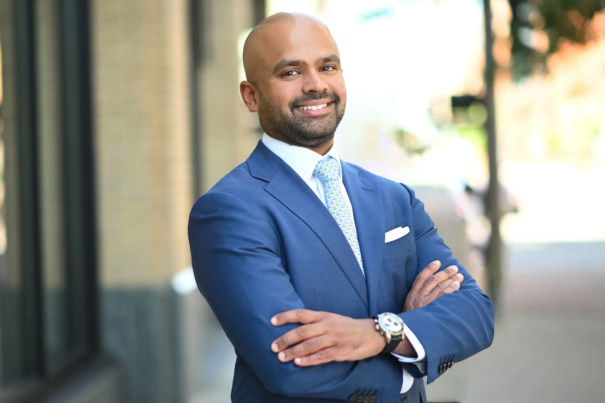 On-location headshot in Denver: blue suit, arms crossed, on a city street