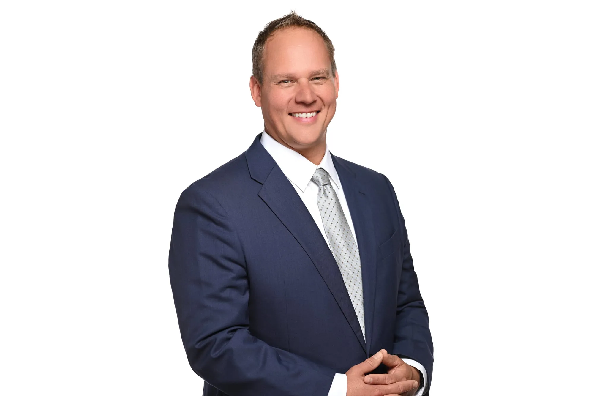 Studio headshot on a white background: navy suit and silver tie