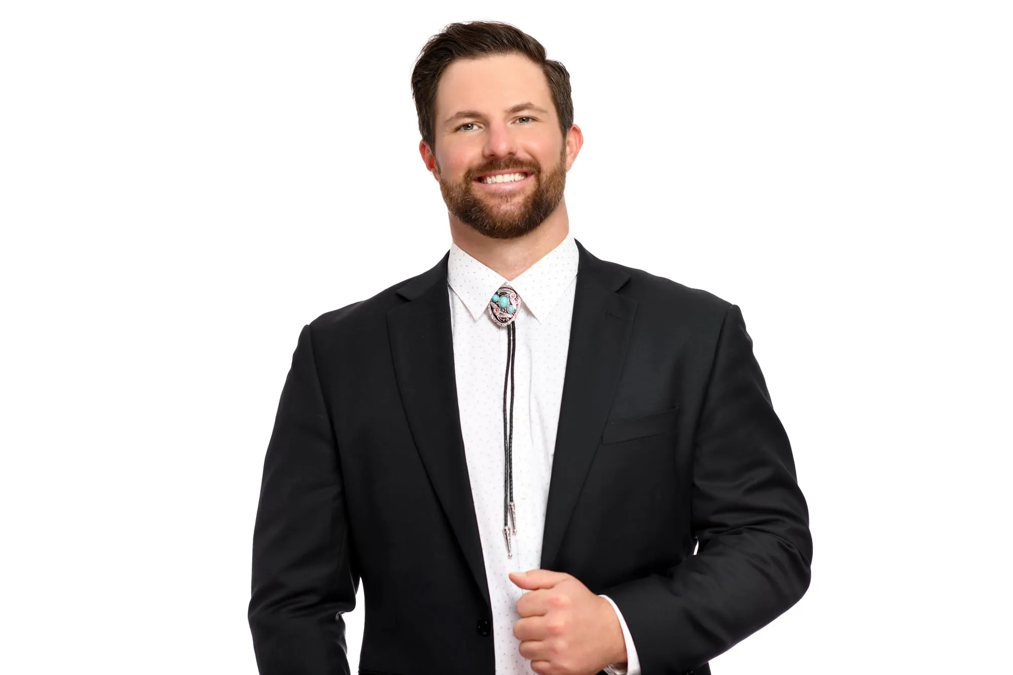 Studio headshot on a white background: black suit with a bolo tie