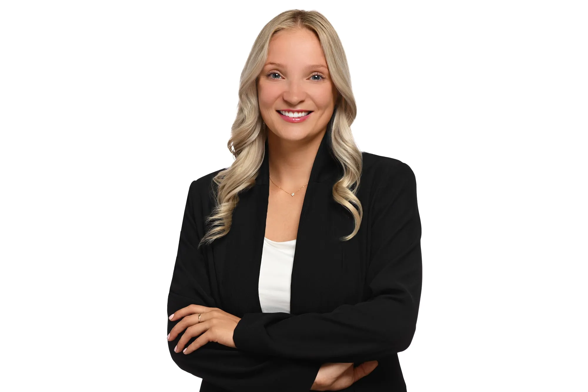 Studio headshot on a white background: black blazer and long wavy hair, arms crossed