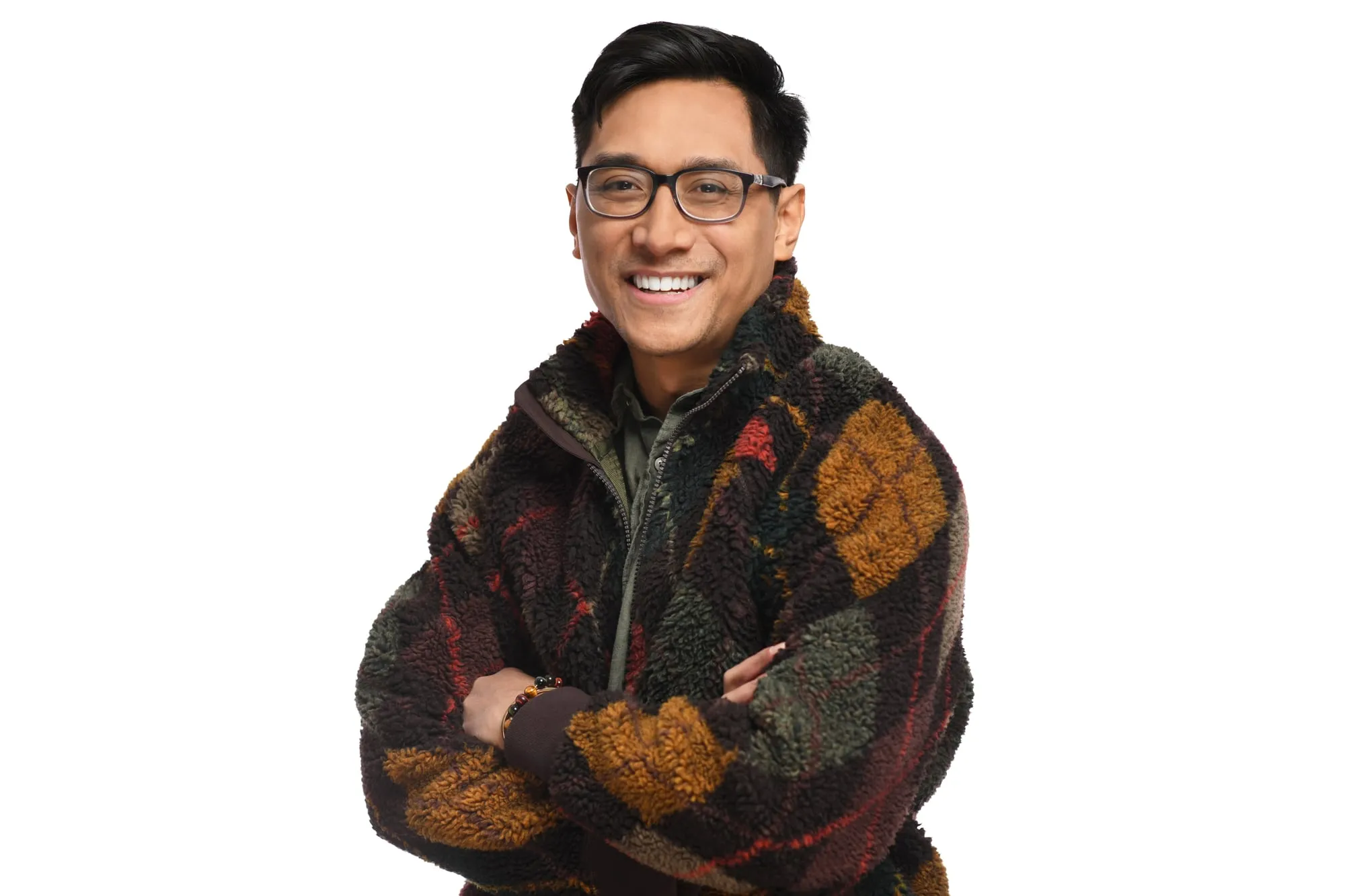 Studio headshot on a white background: patterned knit jacket and glasses, arms crossed