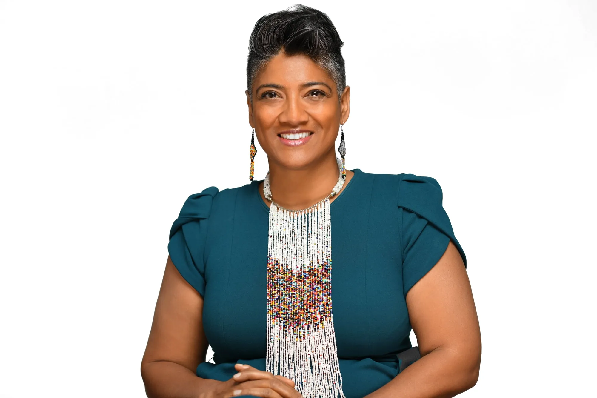 Studio headshot on a white background: teal blazer with a beaded necklace