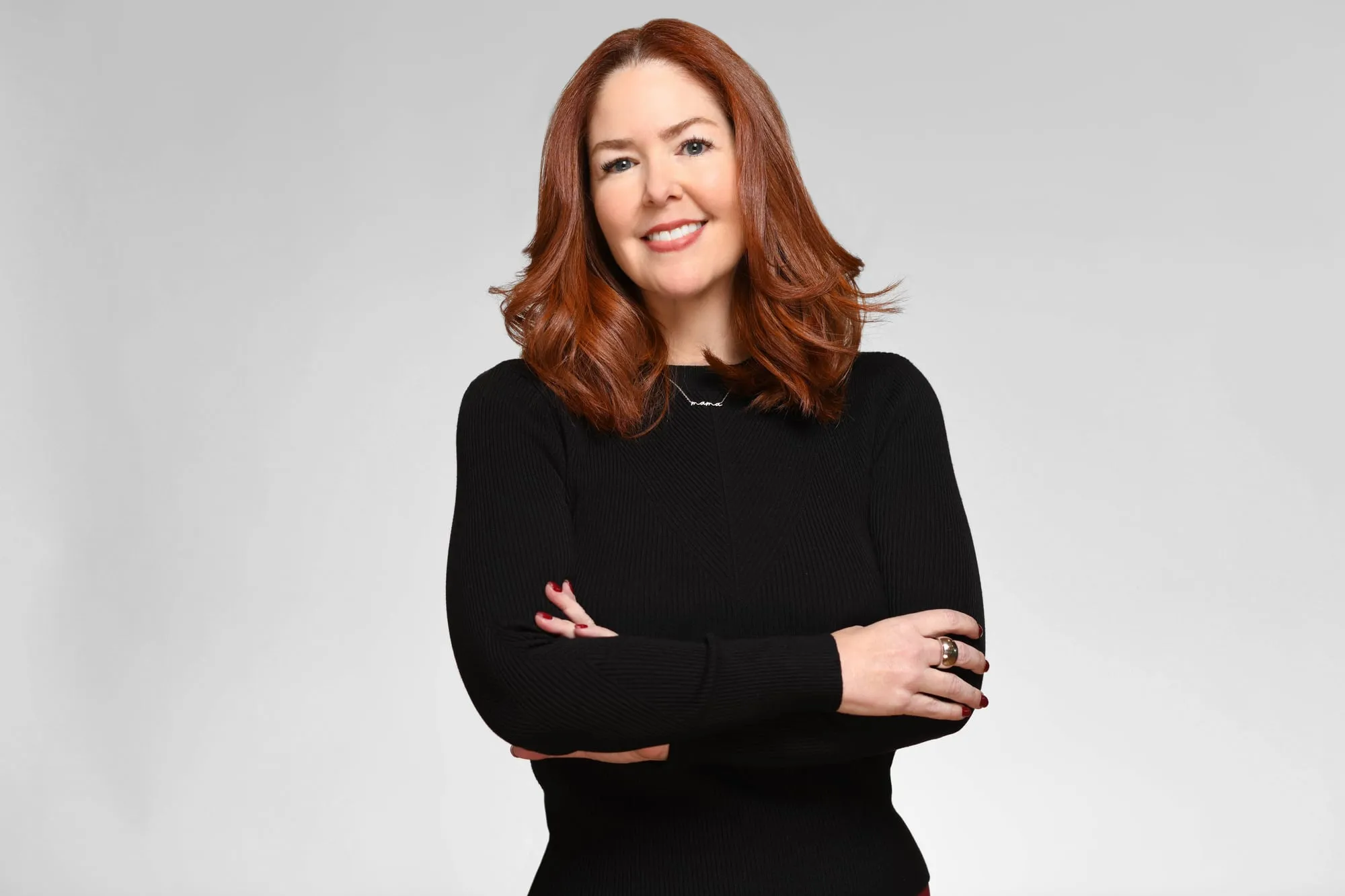 Corporate headshot for Tract in Denver on a light grey background: black top, arms crossed