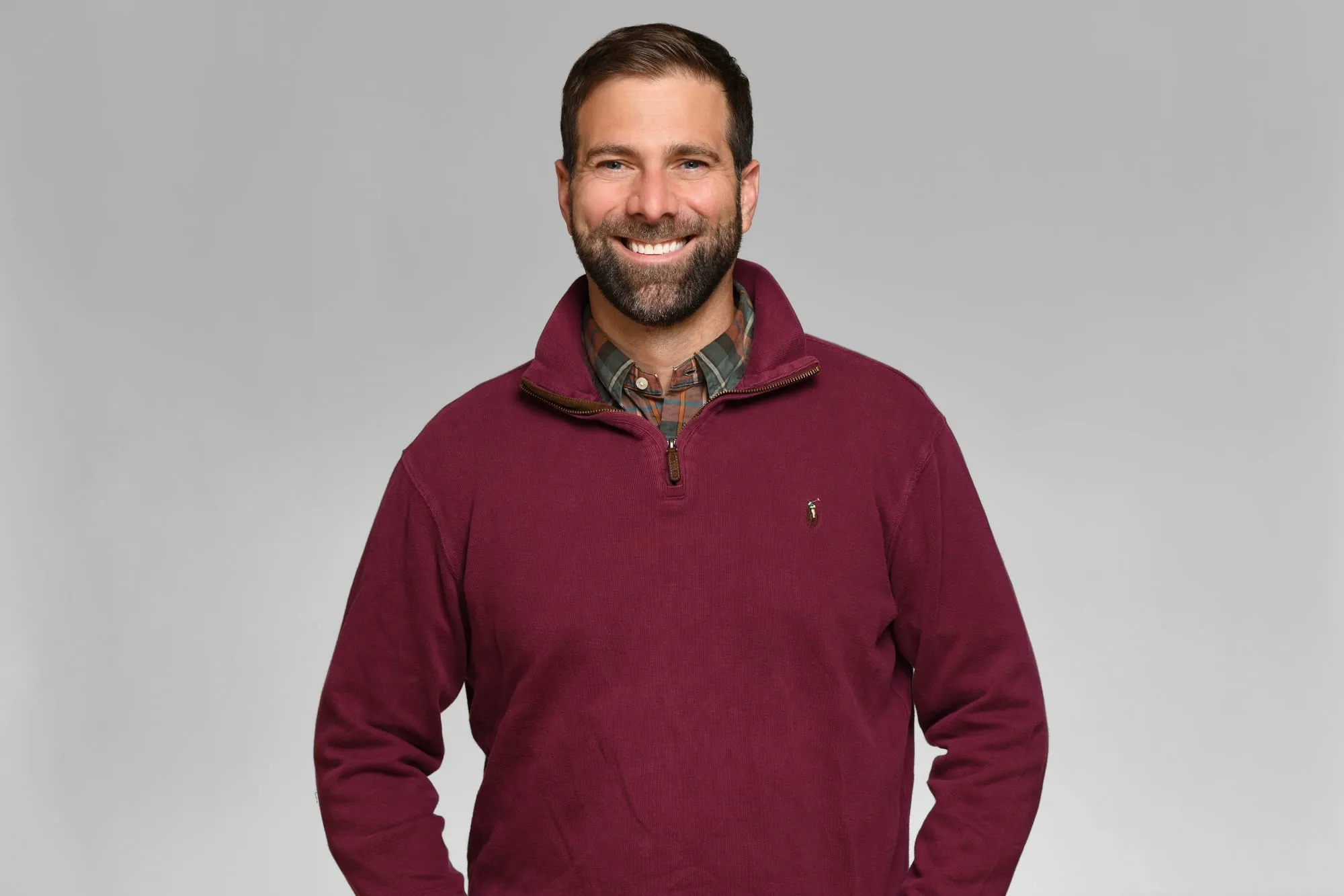 Corporate headshot for Tract in Denver on a light grey background: burgundy quarter-zip