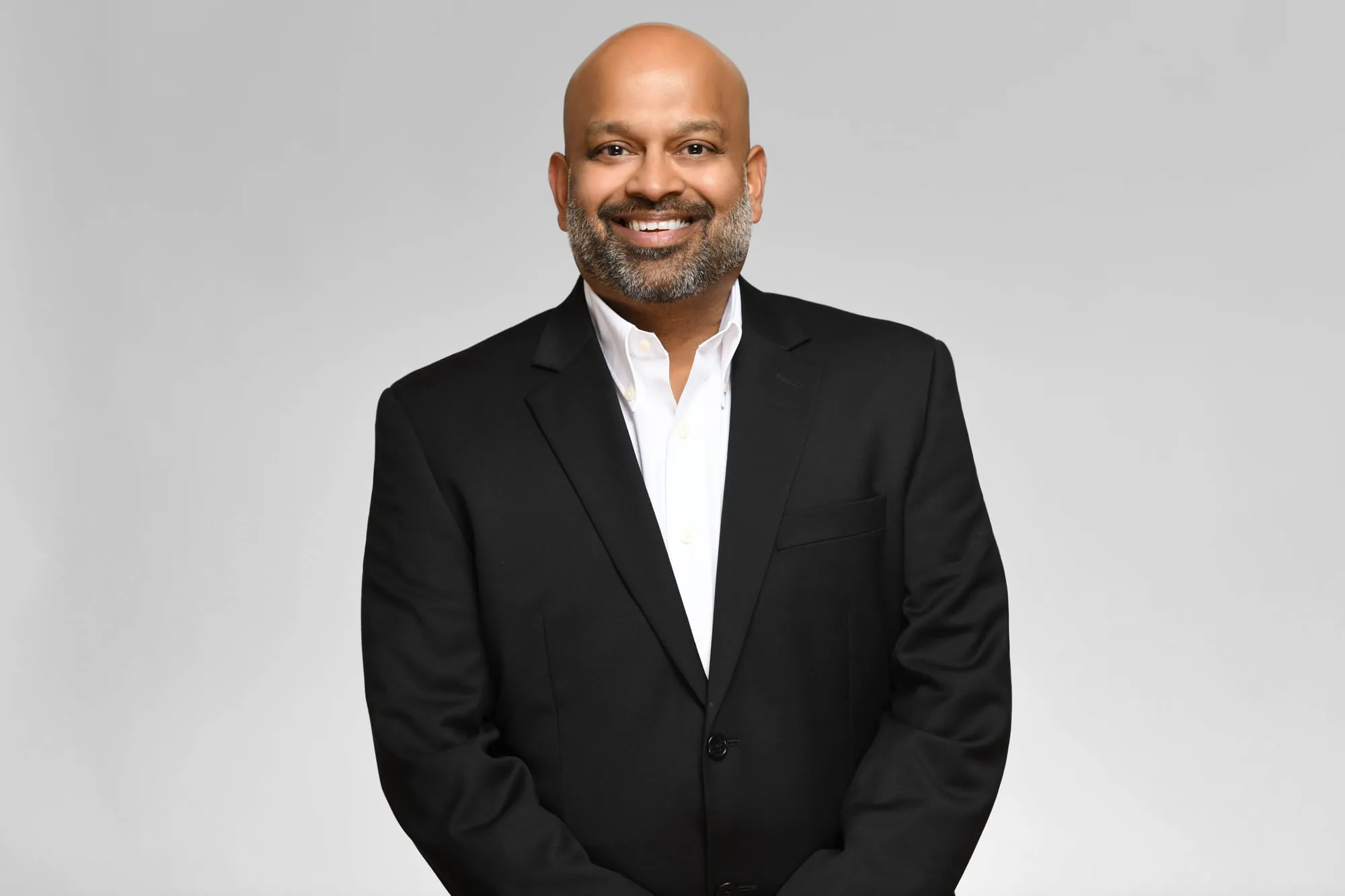 Corporate headshot for Tract in Denver on a light grey background: black blazer and white shirt